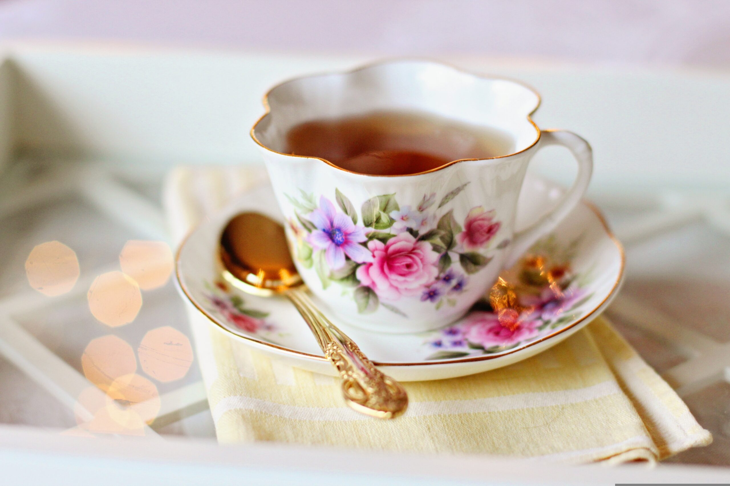 Floral china teacup set holding tea with a golden spoon the saucer. Image source Pixabay.