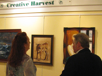 Two people looking at painting at the Creative Harvest exhibit